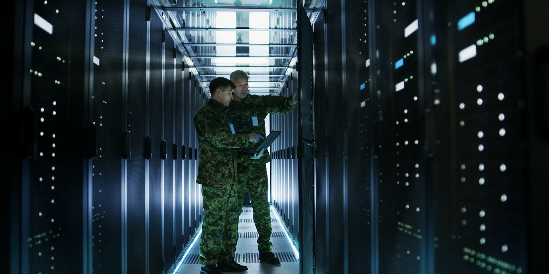 cybersecurity defense - two men in army fatigues in server rack room